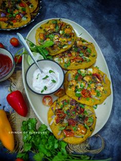 some tacos are sitting on a plate with dip and vegetables next to the plates