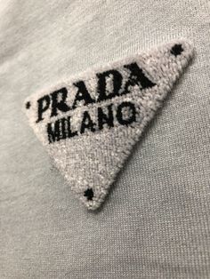 an embroidered patch on the back of a gray shirt that says, prada milano