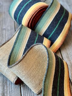 two ties laying on top of each other on a wooden table next to an orange and green striped tie