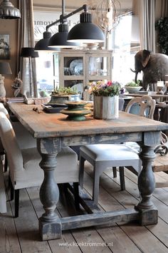 an old wooden table with chairs and vases on it in a room filled with furniture