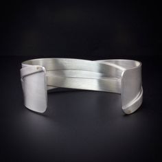 Sterling silver woven cuff bracelet that has 18K Gold rivets.  A unique contemporary cuff design where the cuff has been sawed, woven and riveted to give it a unique look.  The surface can be brushed matte or have a shiny polished finish. The cuff is made to order for your size wrist see drop down menu for sizes and finish.   Photos 1 thru 4 show the cuff in a matte finish and photo 5 shows the cuff in a polished shiny finish.  The cuff bracelet is 0875 inch (22.23) wide at the ends and 0.625... Contemporary Formal Cuff Bracelet Bangle, Unique Cuff Bracelet For Formal Occasions, Contemporary Polished Cuff Bracelets, Contemporary Cuff Bracelet With Polished Finish, Contemporary Polished Cuff Bracelet, Modern Cuff Bracelets With Polished Finish, Modern Twist Cuff Bracelet Bangle For Formal Occasions, Modern Twist Bangle Cuff Bracelet For Formal Occasions, Modern Twist Cuff Bracelet For Formal Occasions