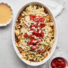 a white bowl filled with salad next to a small bowl of dressing and a spoon