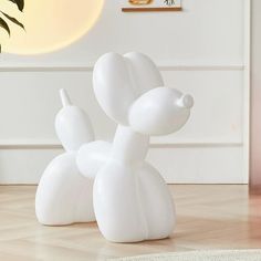 a large white balloon dog sitting on top of a wooden floor