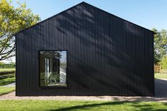 a black building with an open window on the side and grass in front of it