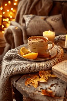 a cup of hot chocolate with lemon slices on a plate next to an open book