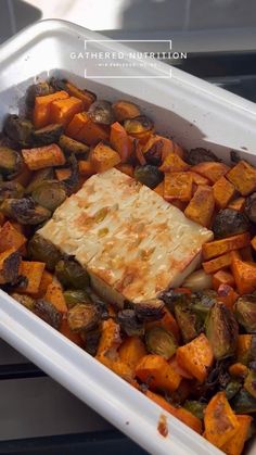 a white container filled with vegetables and tofu