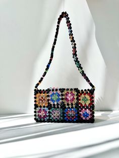 a beaded purse sitting on top of a white table next to a shadow wall