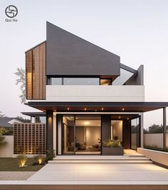 a modern house is shown at dusk with its lights on and the front door open