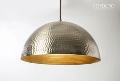 a large metal dome light hanging from a ceiling fixture with a gold finish on it