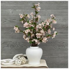 a white vase filled with pink flowers sitting on top of a table next to headphones