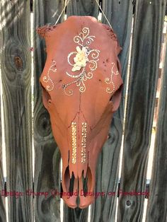 a cow's skull hanging on a wooden fence with beads and chains attached to it