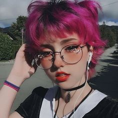 a woman with pink hair wearing glasses and headphones