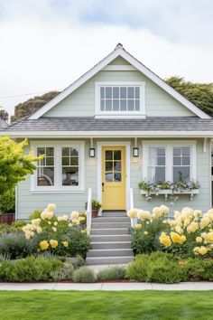 a house with yellow flowers in the front yard and steps leading up to the front door