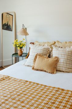 a bed with yellow and white checkered comforter on top of it in a bedroom