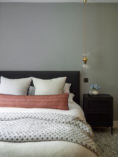 a bedroom with a bed, night stand and two lamps on the wall above it