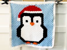 a crocheted penguin with a santa hat hanging on a clothes line