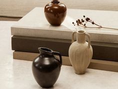 two vases sitting on top of a table next to a book