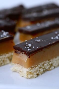 pieces of dessert sitting on top of a plate with white and brown toppings around it