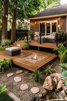 an outdoor deck with seating and fire pit surrounded by greenery, rocks and trees