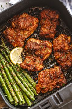 chicken and asparagus in a skillet with lemon wedges on the side