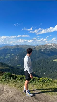 a man standing at the top of a mountain looking out over a valley and mountains