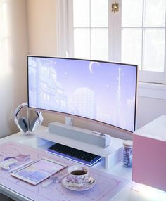 a computer monitor sitting on top of a desk next to a cup and headphones