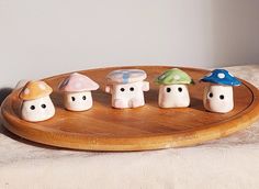 five small ceramic mushrooms sitting on top of a wooden tray