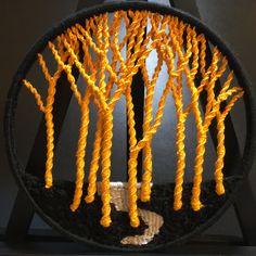 an artistic sculpture made out of plastic orange trees on display in front of a black background