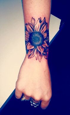 a woman's arm with a sunflower tattoo on the left side of her wrist