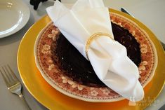 a plate topped with a chocolate cake covered in icing and a napkin on top of it