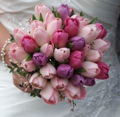 a bride holding a bouquet of pink and purple tulips