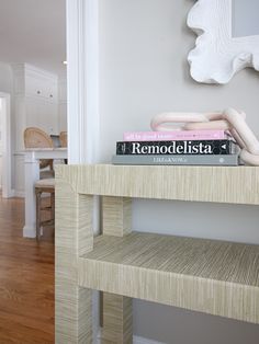 a stack of books sitting on top of a wooden table next to a white wall