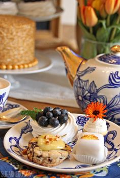 an assortment of desserts on a blue and white plate with flowers in the background