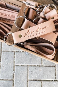 several pairs of leather key chains in a box on the ground next to a brick sidewalk