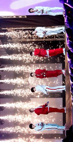 four men in red and white outfits standing on stage with their hands behind their backs