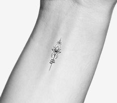 a woman's wrist with a small flower tattoo on the left side of her arm