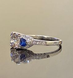 DeKara Designs Collection Beautiful Modern/Art Deco Diamond Blue Sapphire Pave Set Engagement Ring. Metal- 90% Platinum, 10% Iridium. Stones- 1 Genuine Round Diamond K-L Color VS1-VS2 Clarity 1.01 Carats, 96 Round Diamonds H-I Color SI1 Clarity 0.52 Carats, 2 Special Cut Trapezoid Blue Sapphires 0.40 Carats. Size- 6 1/2. FREE SIZING A Jaw Drop Gorgeous Art Deco Inspired Round Diamond Center Special Cut Blue Sapphire Diamond Engagement Ring Handmade in Platinum. There is a beautiful expertly pron Exquisite Sapphire Diamond Ring With Vvs Clarity, Luxury Gia Certified White Sapphire Ring, Timeless White Sapphire Ring With Diamond, Exquisite Sapphire Rings With Brilliant Cut, Timeless Blue Sapphire Wedding Ring, Classic Sapphire Jewelry Gia Certified, Classic Gia Certified Sapphire Jewelry, Art Deco Sapphire Ring With Gia Certified Diamond, Art Deco Gia Certified Round Cut Sapphire Ring