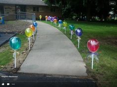 there are many colorful balloons on the side of the road in front of a house