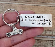 a hand holding a metal keychain that says drive safe i need you here with me