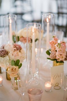 the centerpieces on this table are filled with flowers and candles for an elegant touch