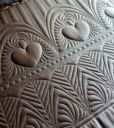 a close up view of a quilted surface with heart shapes on the top and bottom