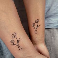 two people with matching tattoos on their arms holding each other's hands and one has a