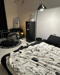 an unmade bed with black and white sheets on the floor next to a lamp