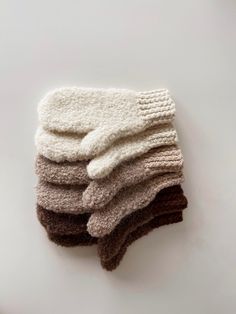 five knit mittens stacked on top of each other