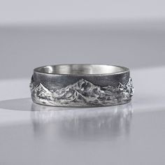 a silver ring with mountains in the background and an inscription that says ship's next day