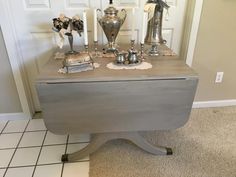 a table with silver vases and other items on it in front of a door