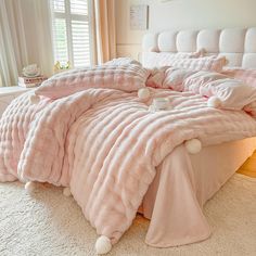 a bed covered in pink blankets and pillows