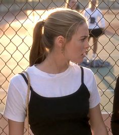 a woman standing in front of a chain link fence