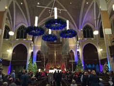 a large church filled with lots of people and decorated for the holiday season in blue lights