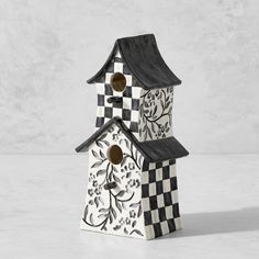 a black and white birdhouse with a checkerboard design on the roof is shown